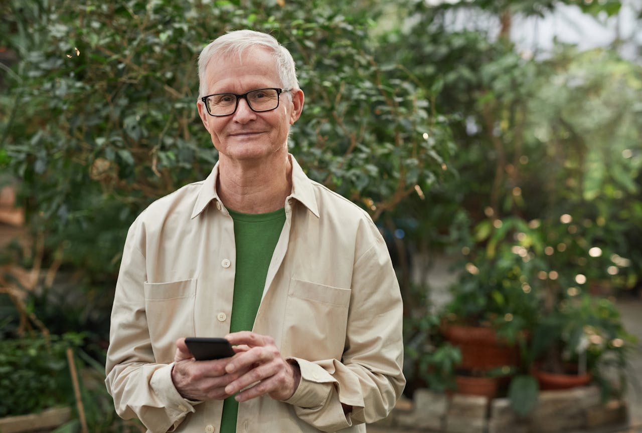 Smiling man wearing eyeglasses and holding a cell phone